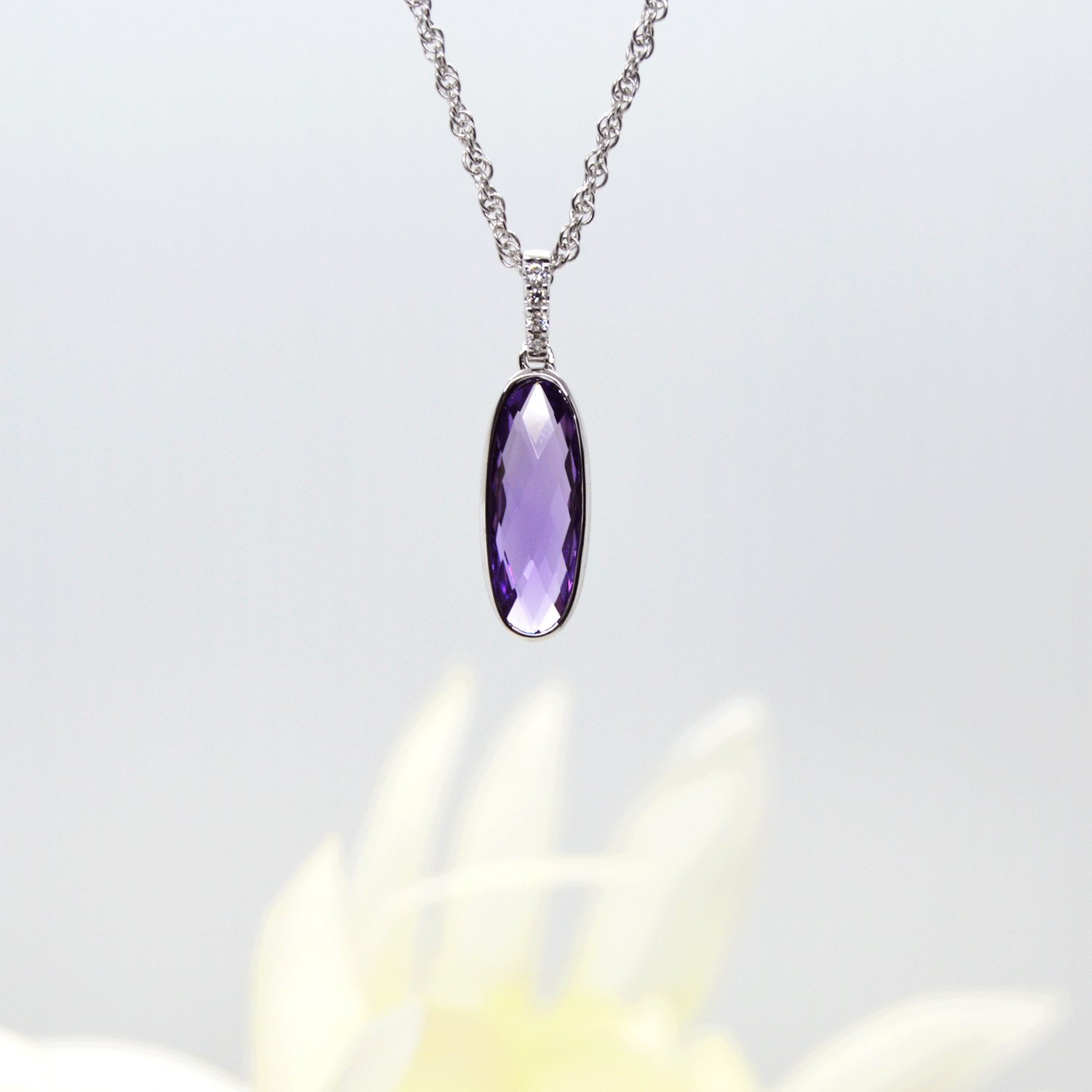 Elongated oval checkerboard-cut amethyst gemstone in 14k white gold pendant with diamond bail. Allison Kaufman