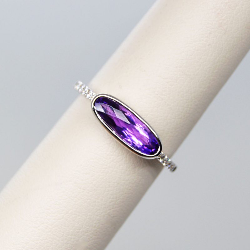 Elongated oval checkerboard-cut amethyst gemstone in 14k white gold ring with diamond accents. Allison Kaufman