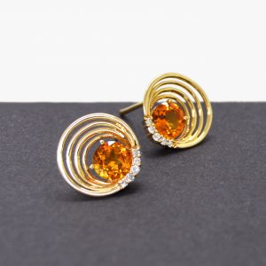 Citrine and diamond stud earrings in 14k yellow gold settings with asymmetrical concentric cirles and diamond accents