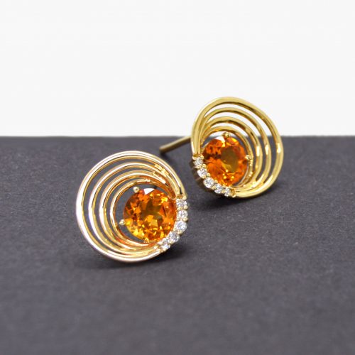 Citrine and diamond stud earrings in 14k yellow gold settings with asymmetrical concentric cirles and diamond accents