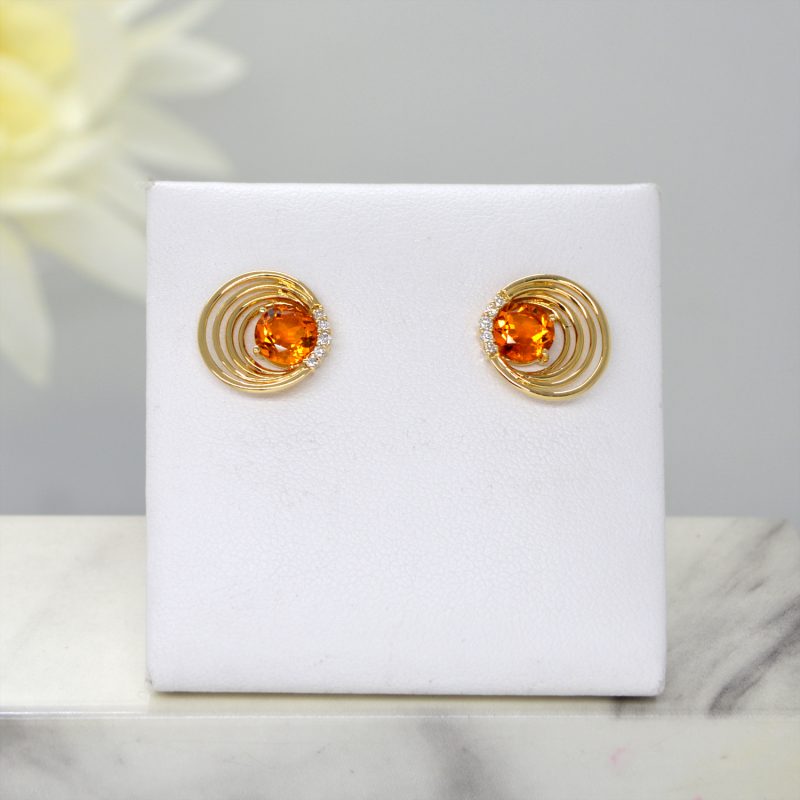 Citrine and diamond stud earrings in 14k yellow gold settings with asymmetrical concentric cirles and diamond accents