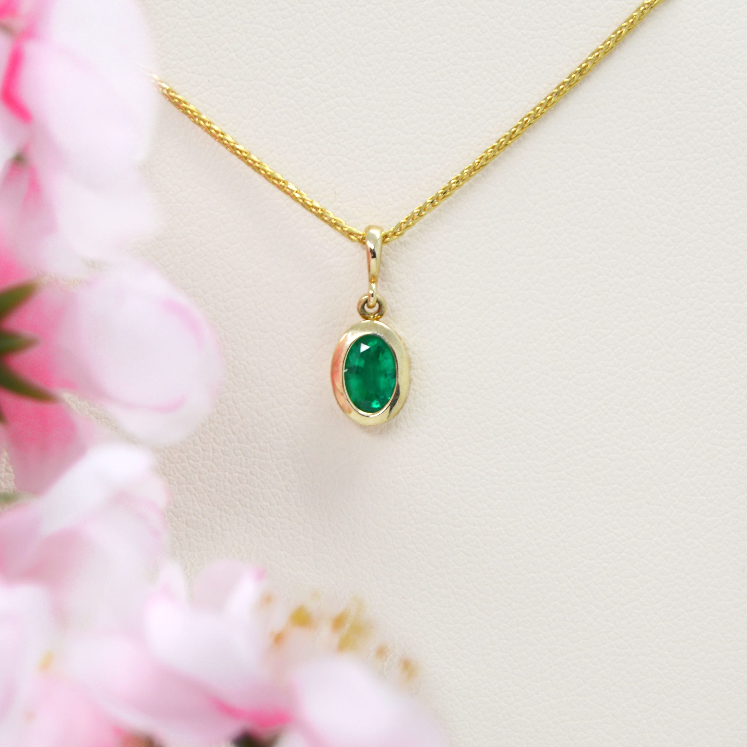 Oval Emerald pendant bezel-set in 14KT yellow gold