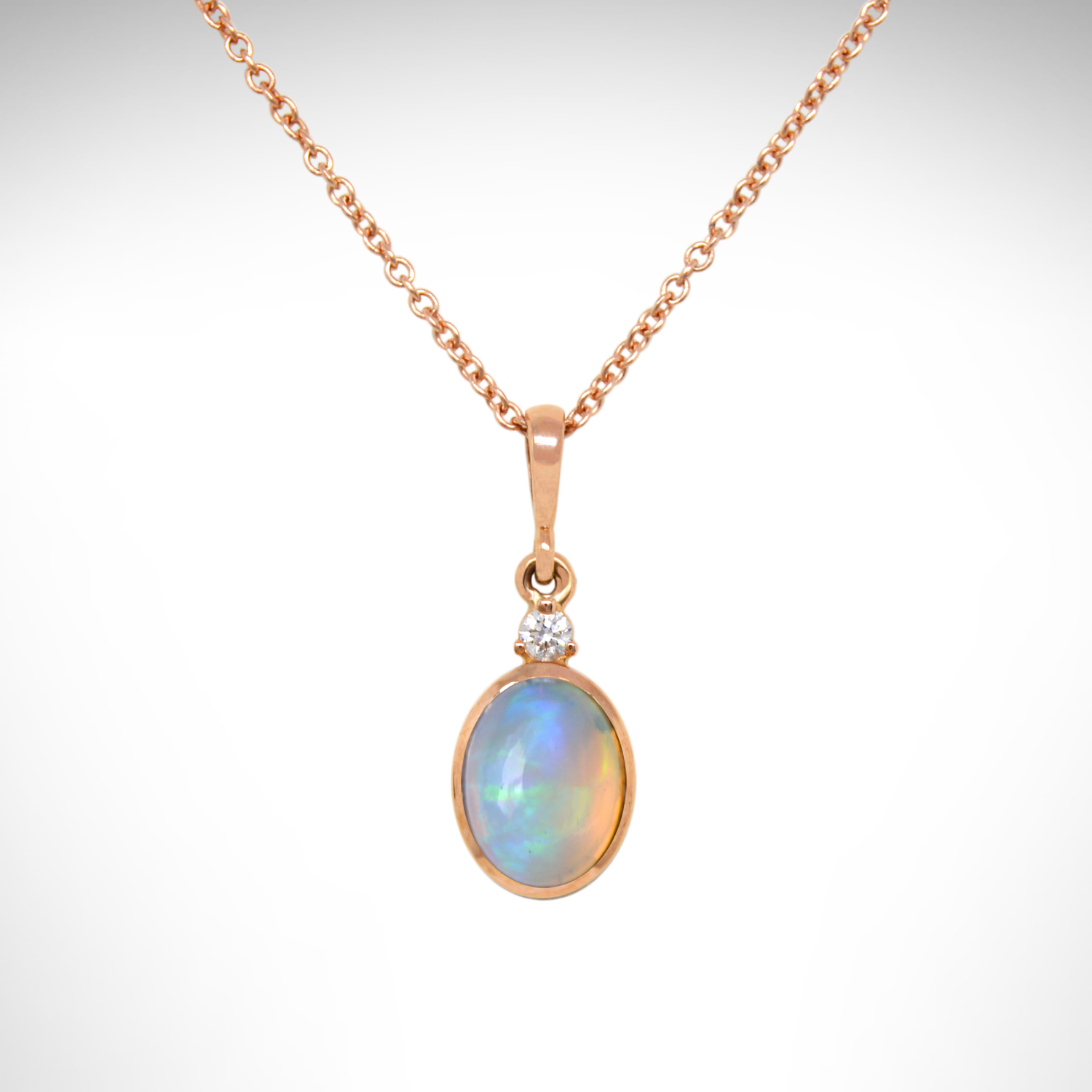 Ethiopian opal oval bezel set dangle necklace in 14k rose gold with an accent diamond