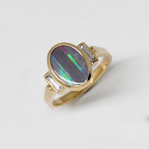 Australian Boulder Opal natural oval gemstone, bezel set oval three stone ring with baguette diamonds in 14k yellow gold ring. Designed by Morgan's Treasure in Westerville, OH