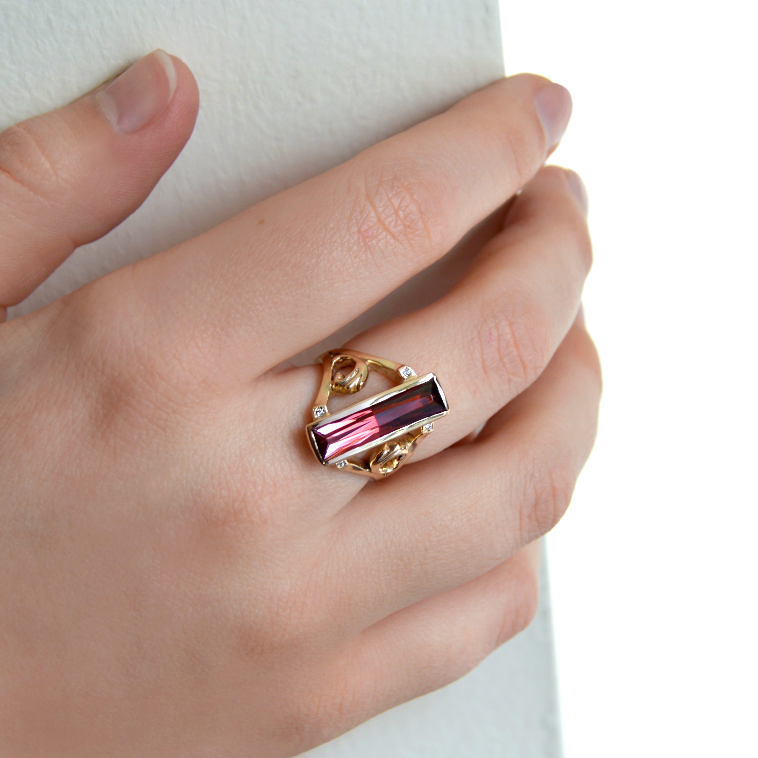 Pink tourmaline ring in yellow gold with scrolls and accent diamonds.
