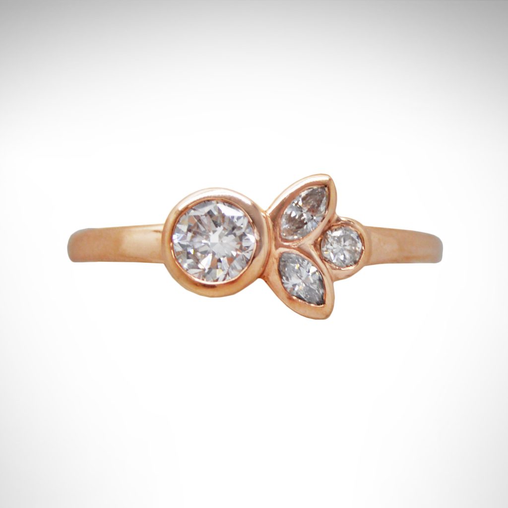 14k rose gold diamond ring with bezel-set round and marquise diamonds and simple band, minimalist design with floral/ leaf inspiration.