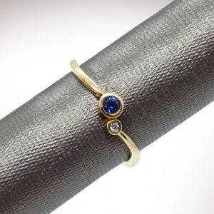 14k yellow gold stackable ring with bezel set diamond and 3mm sapphire gemstones.
