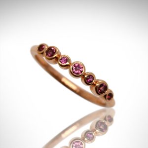 Pink tourmaline ring in alternating sizes of round bezel set stones in 14k rose gold, stackable ring